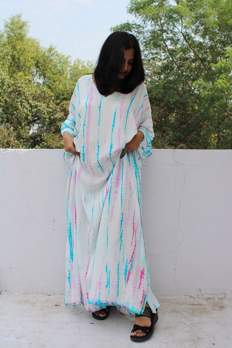 May include: A white maxi dress with blue and pink tie-dye pattern. The dress has a V-neck and long sleeves.