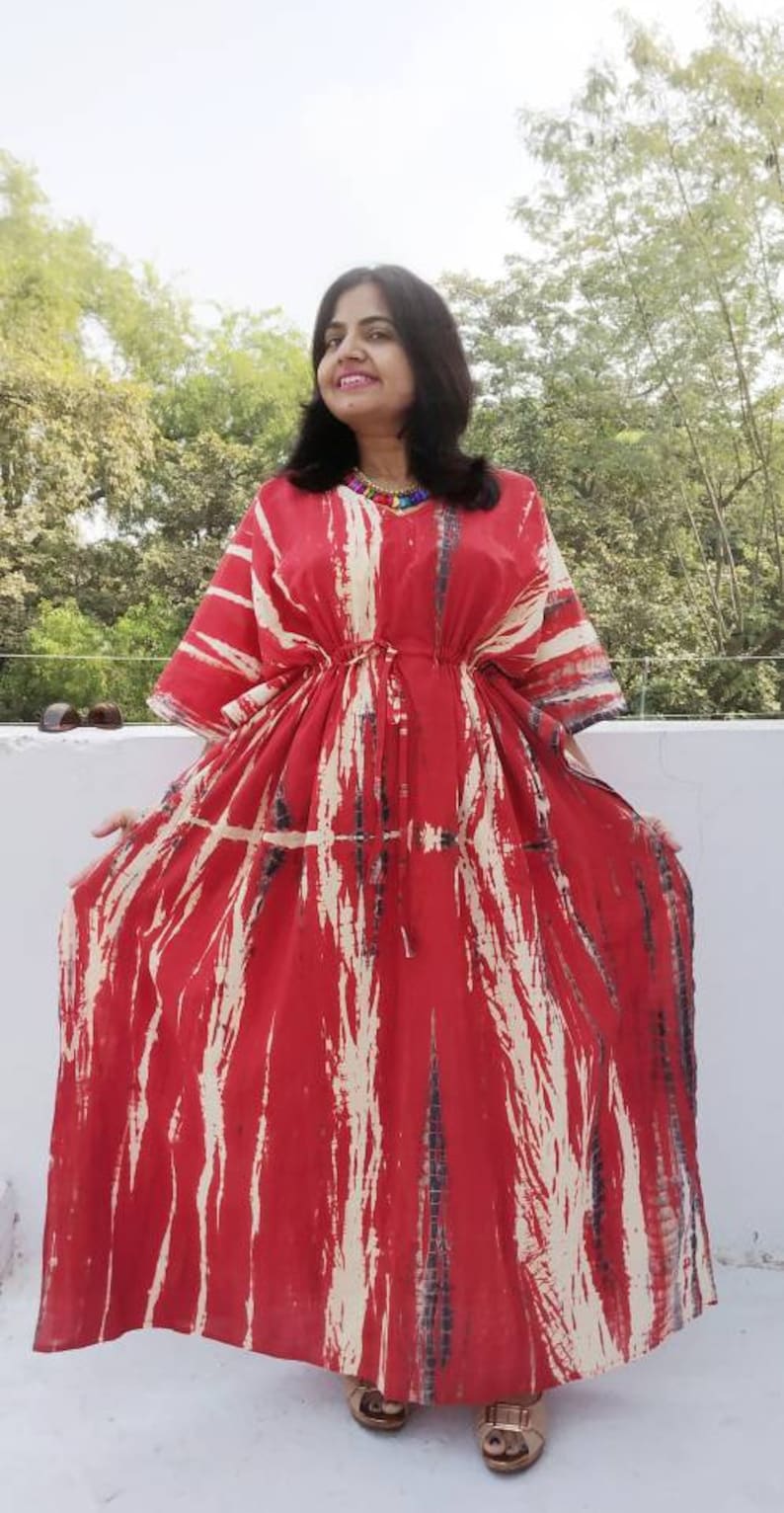 Puede incluir: Un vestido kaft&aacute;n de color rojo y blanco con estampado tie-dye y cintura con cord&oacute;n. El vestido tiene un corte holgado y es perfecto para un look casual de verano.