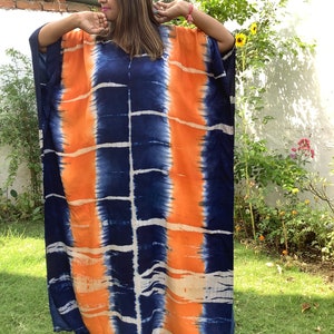 May include: A long, flowing, blue and orange tie-dye kaftan dress. The dress has a loose, comfortable fit and is perfect for warm weather.