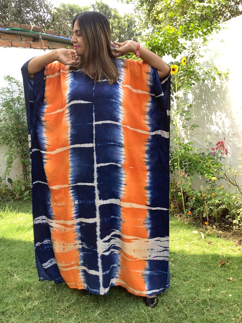 May include: A long, flowing, blue and orange tie-dye kaftan dress. The dress has a loose, comfortable fit and is perfect for warm weather.
