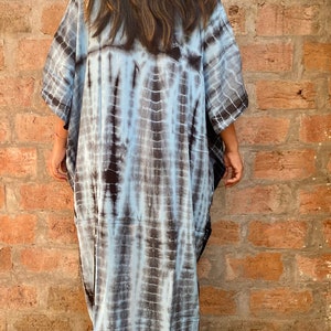May include: A long, flowing, blue and black tie-dye kaftan dress. The dress has a loose, comfortable fit and is perfect for a casual, bohemian look.
