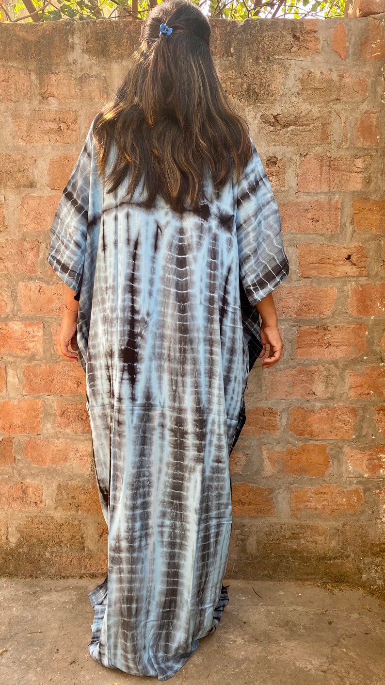 May include: A long, flowing, blue and black tie-dye kaftan dress. The dress has a loose, comfortable fit and is perfect for a casual, bohemian look.