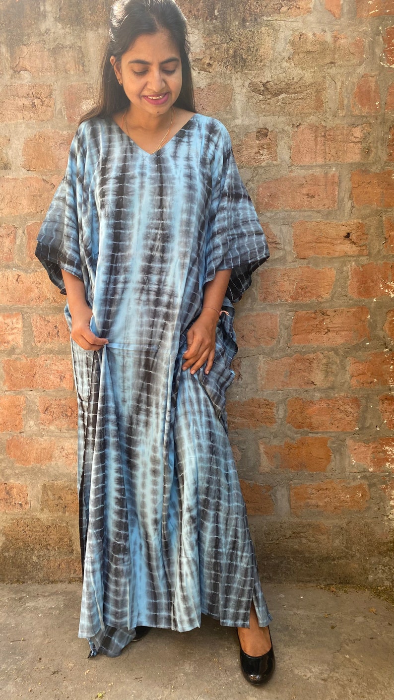 May include: A long, flowing blue and black tie-dye kaftan with a V-neckline and short sleeves. The kaftan is made of a soft, comfortable fabric and has a relaxed fit.