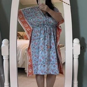 May include: A blue and white floral print kaftan with orange trim. The kaftan has a V-neck, short sleeves, and a drawstring waist.