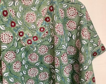 May include: A green cotton kaftan with a floral print in shades of red, white, and blue. The kaftan has a V-neck and short sleeves.