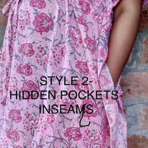 May include: A light pink floral patterned caftan with hidden pockets and inseams. The caftan features a floral design in shades of pink and purple. The text "STYLE 2 - HIDDEN POCKETS - INSEAMS" is printed on the front.