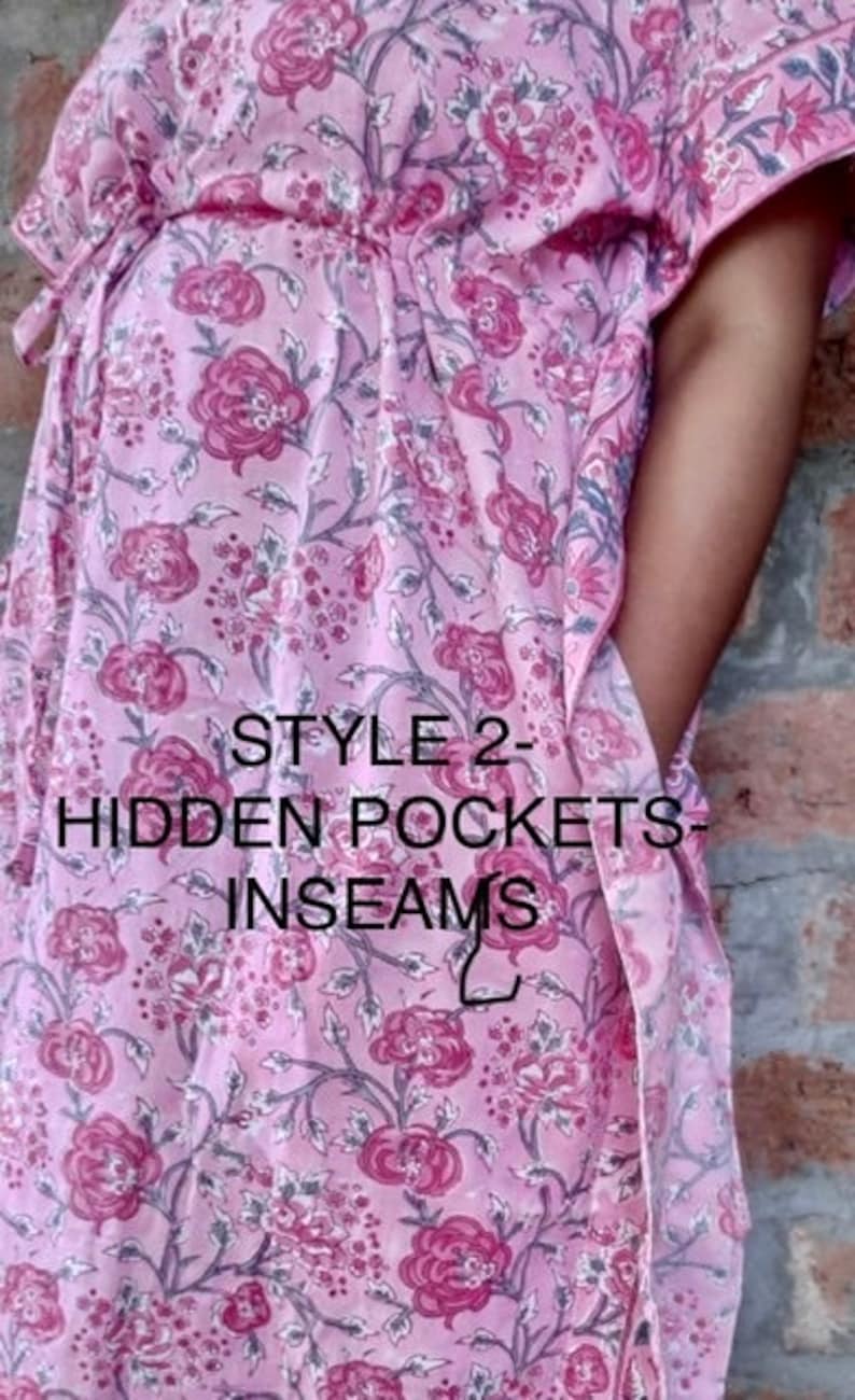 May include: A light pink floral patterned caftan with hidden pockets and inseams. The caftan features a floral design in shades of pink and purple. The text "STYLE 2 - HIDDEN POCKETS - INSEAMS" is printed on the front.
