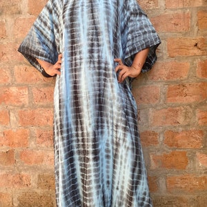 May include: A long, flowing blue and black tie-dye kaftan dress with a V-neckline and short sleeves.