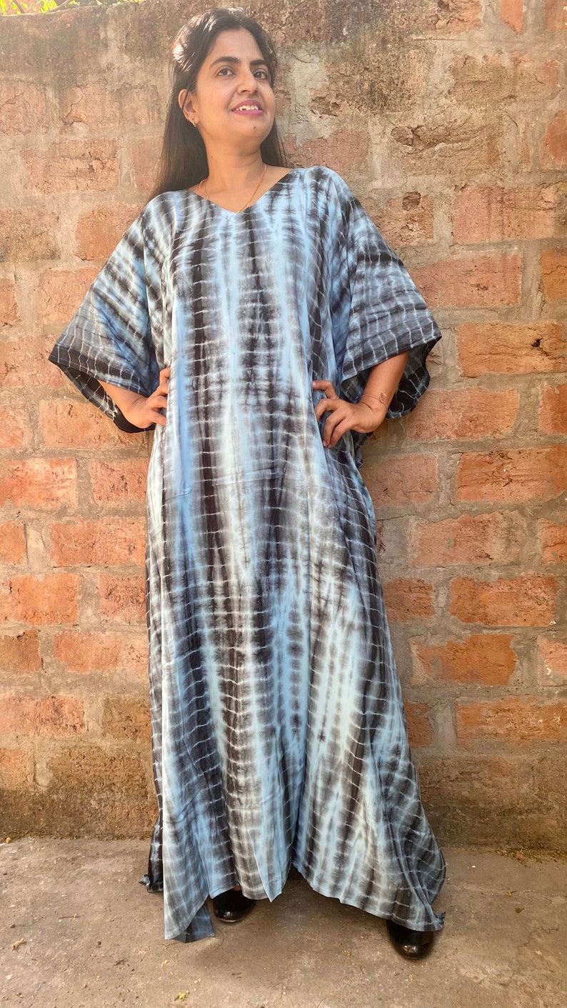 May include: A long, flowing blue and black tie-dye kaftan dress with a V-neckline and short sleeves.
