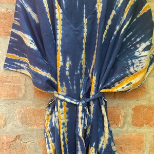 May include: A blue and yellow tie-dye kaftan with a V-neck and a tie belt.