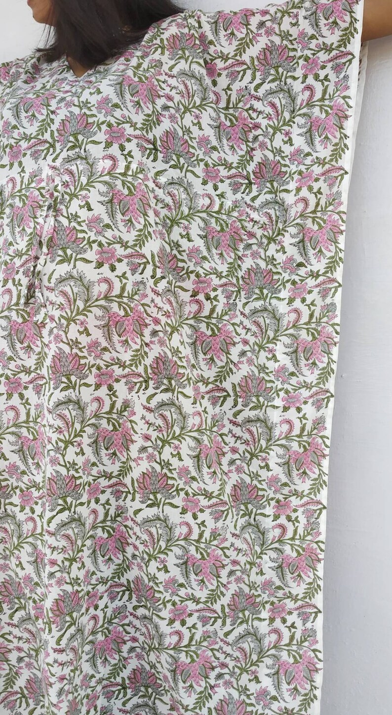May include: White cotton kaftan with a pink and green floral print. The kaftan has a V-neck and a loose, flowing fit.