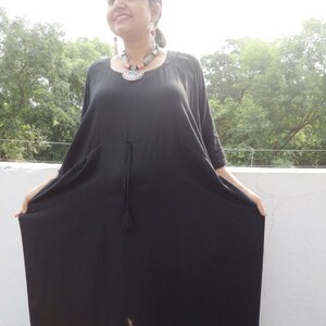 May include: A black maxi dress with a drawstring waist and short sleeves. The dress is made of a soft, flowing fabric.