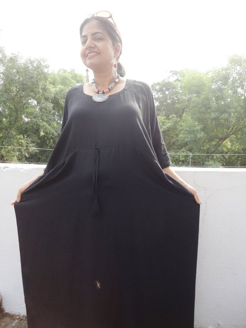 May include: A black maxi dress with a drawstring waist and short sleeves. The dress is made of a soft, flowing fabric.