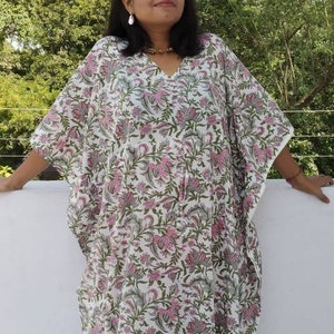 May include: A white kaftan with a pink and green floral print. The kaftan has a V-neck and long sleeves.