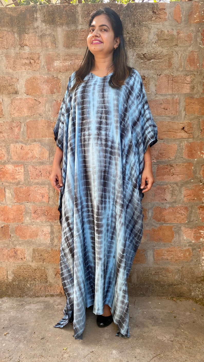 May include: A long, flowing blue and black tie-dye kaftan dress with a relaxed fit. The dress has a round neckline and short sleeves.