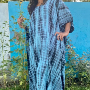 May include: A woman wearing a blue and black tie-dye kaftan dress. The dress has a loose, flowing fit and is made of a soft, comfortable fabric.