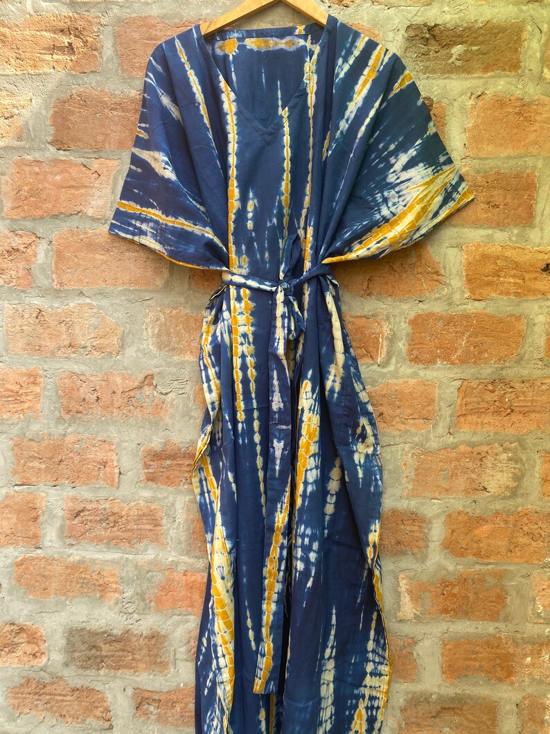 May include: A blue and yellow tie-dye kaftan with a V-neck and a tie belt.