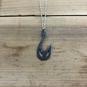 May include: A silver chain necklace with a pendant shaped like a fishing hook with a deer silhouette inside.