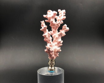 May include: A pink coral lamp finial with a silver base. The finial is on a clear acrylic pedestal.