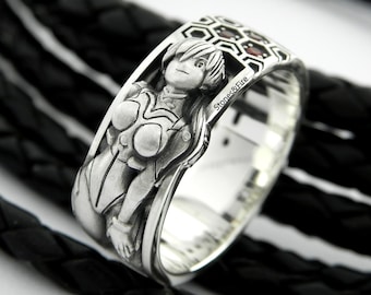 May include: A silver ring with a detailed design of a woman in a futuristic outfit. The ring has a honeycomb pattern with red gemstones and the words "Stones&Fire" engraved on the side.