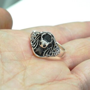 May include: A silver ring with a detailed design of a hollow bug character.