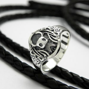 May include: A silver ring with a detailed design featuring a knight's helmet and wings.