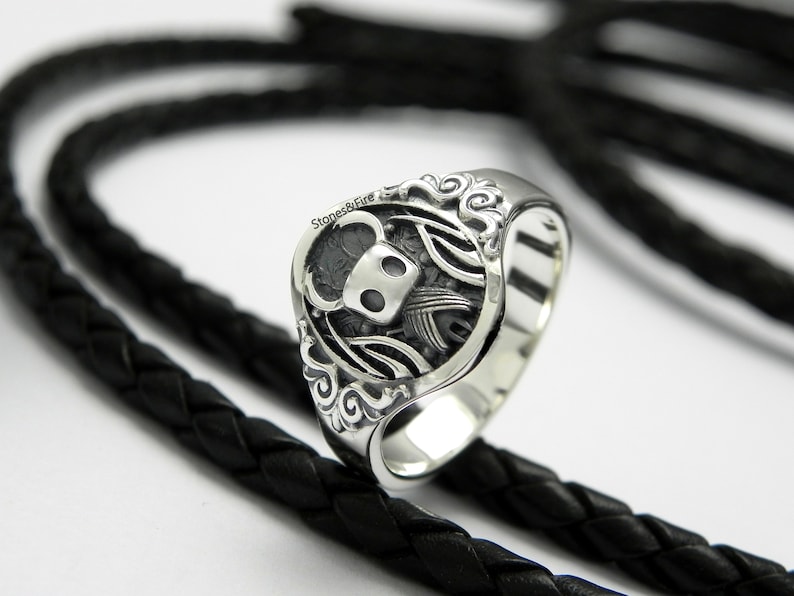 May include: A silver ring with a detailed design featuring a knight's helmet and wings.