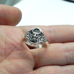 May include: A silver ring with a detailed design featuring a tiny knight.