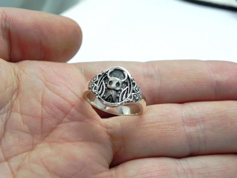 May include: A silver ring with a detailed design featuring a tiny knight.