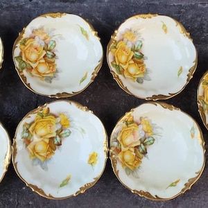 May include: Set of six white porcelain bowls with gold trim and yellow rose floral designs.