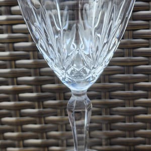 May include: A clear glass wine glass with a cut crystal design. The glass has a tall stem and a wide base.