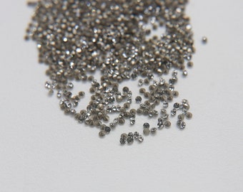 May include: A pile of small, clear, faceted rhinestones on a white background.