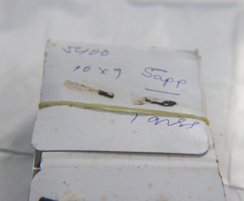 Op de afbeelding: Een wit label met blauwe inkt staat er "5400 10 x 7 Sapp 1 onss" op.