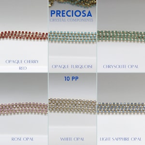 May include: Six rows of square-shaped crystal beads in various colours, including red, turquoise, green, pink, white, and blue. The beads are connected by gold-coloured metal links. The text "PRECIOSA CRYSTAL COMPONENTS" and "10 PP" are visible above the beads. The text below each row of beads identifies the colour of the beads: "OPAQUE CHERRY RED", "OPAQUE TURQUOISE", "CHRYSOLITE OPAL", "ROSE OPAL", "WHITE OPAL", and "LIGHT SAPPHIRE OPAL".