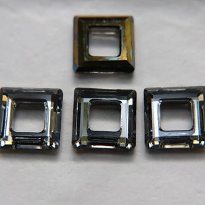 Può includere: Quattro strass quadrati in vetro trasparente con un foro al centro. Gli strass sono di colore grigio scuro con un leggero effetto iridescente.
