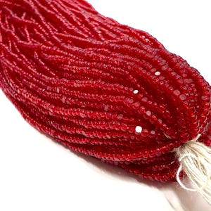 May include: A bundle of red seed beads, approximately 100 grams, tied together with a white string.