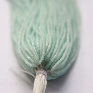 May include: A strand of light blue seed beads, with a white thread tied at the end.
