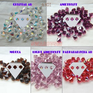 Puede incluir: Surtido de cristales bicónicos Swarovski 6301 en varios colores, incluyendo Crystal AB, Amatista, Amatista claro, Padparadscha AB y Mocha. Cada color se muestra en una sección separada con una tarjeta blanca que presenta tres agujeros.
