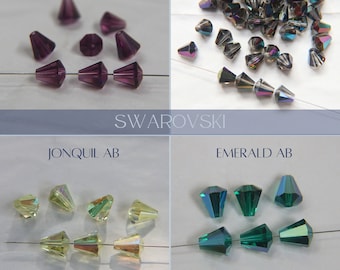 May include: Assortment of Swarovski crystal beads in various colours, including amethyst, emerald AB, jonquil AB, and  'Virrail Medium'. The beads are strung on a thin wire.