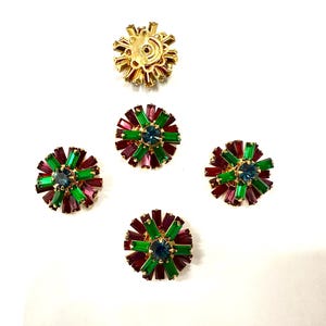 Può includere: Una collezione di orecchini vintage color oro con un design floreale. Ogni orecchino presenta una pietra blu centrale circondata da cristalli rettangolari verdi e bordeaux. Un orecchino è mostrato dal retro.