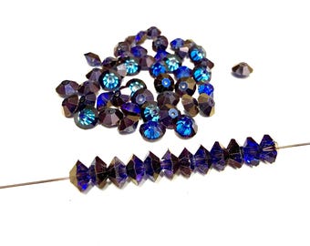 May include: A collection of faceted, dark blue beads with iridescent blue and green highlights. Some beads are loose, while others are strung on a thin wire, showcasing their geometric shapes and reflective surfaces. Ideal for jewelry making.