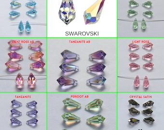 Könnte beinhalten: Sortiment an Swarovski Kristall-Tropfenperlen in verschiedenen Farben, darunter Aquamarin, Kristall, Peridot, Hellrosa, Tansanit und Kristallsatin. Die Perlen sind in Reihen auf einem weißen Hintergrund angeordnet.