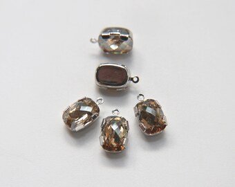 May include: Four silver-toned metal settings with clear, faceted, brown glass stones. The stones are oval-shaped and have a slight shimmer.