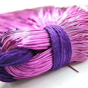 May include: A bundle of pink metallic wire tied together with a purple fabric band. The wire is thin and shiny, and the fabric band is soft and textured.