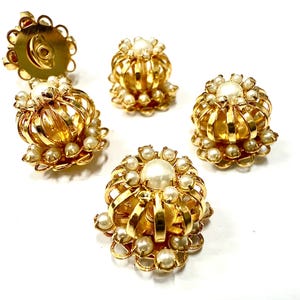 May include: Gold-tone metal earrings with a crown-like design, adorned with small faux pearls. The earrings have a post backing. The design features a large central pearl surrounded by smaller pearls.