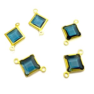 May include: Five gold-colored, square-shaped jewelry components with a teal-colored center stone. Each component has a loop at the top and two loops at the bottom for attachment. The components are displayed on a white background.