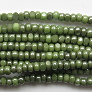 May include: A strand of green glass seed beads. The beads are small and round, with a slightly iridescent finish.