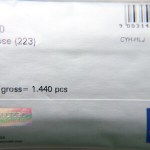 May include: Close-up of a light gray package with the text "5020 MM 3,0 Light Rose (223)". The package also includes a barcode, the text "10/00/00 gross = 1.440 pcs", and the Swarovski logo.