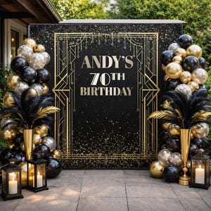 Puede incluir: Un telón de fondo negro con diseño art déco dorado y el texto "ANDY'S 70TH BIRTHDAY". La escena incluye globos dorados, plateados y negros, plumas negras en jarrones dorados y faroles encendidos, creando un ambiente festivo.