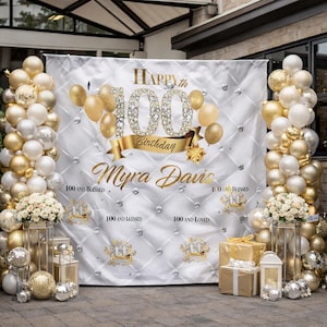 May include: A white backdrop with gold text and decorations for a 100th birthday celebration. The backdrop features the text "Happy 100th Birthday Myra Davis" with gold balloons and diamond accents. Gold and white balloons frame the backdrop.